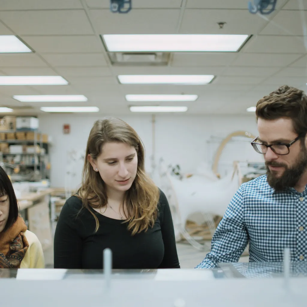 Three people gathered around a computerized textile mill.
